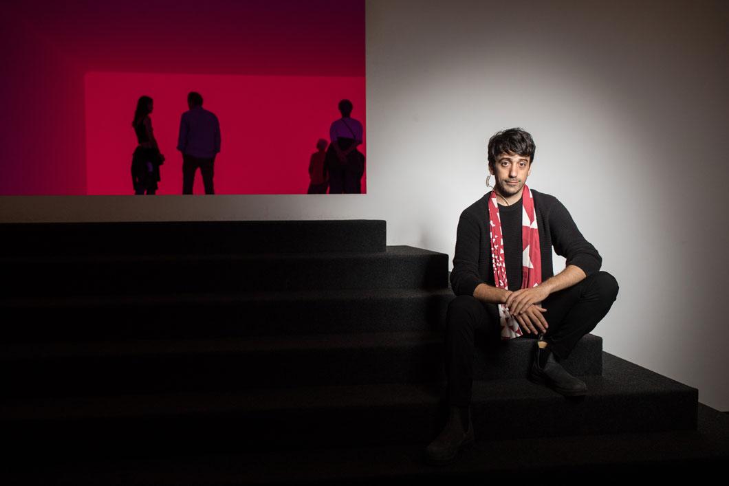 A young man sits on the stairs leading to the installation “Ganzfeld Aural” by James Turrell.