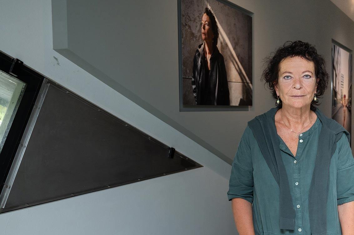 Judith Kessler in front of her portrait in the exhibition ZERHEILT: HEALED TO PIECES, next to her part of a window of the Libeskind building