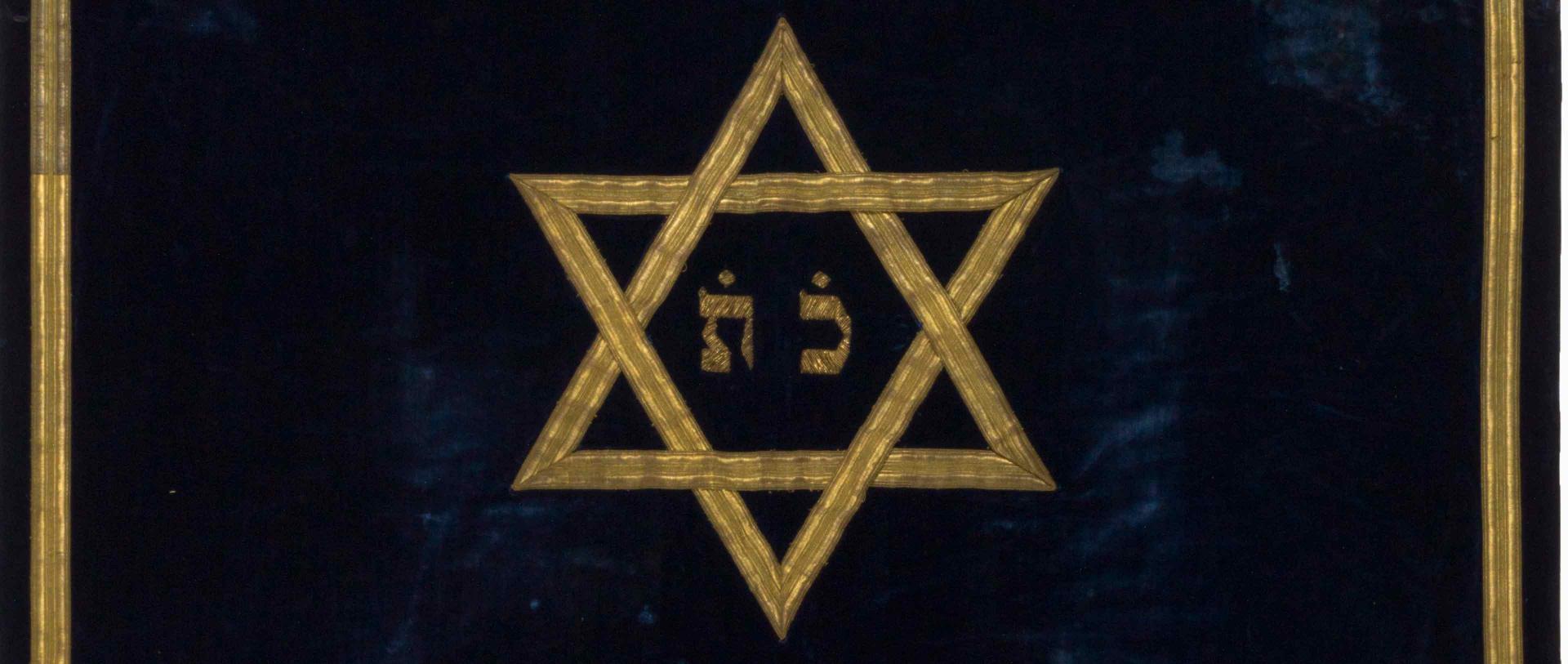 Golden Magen David on dark background, detail from a Torah curtain.
