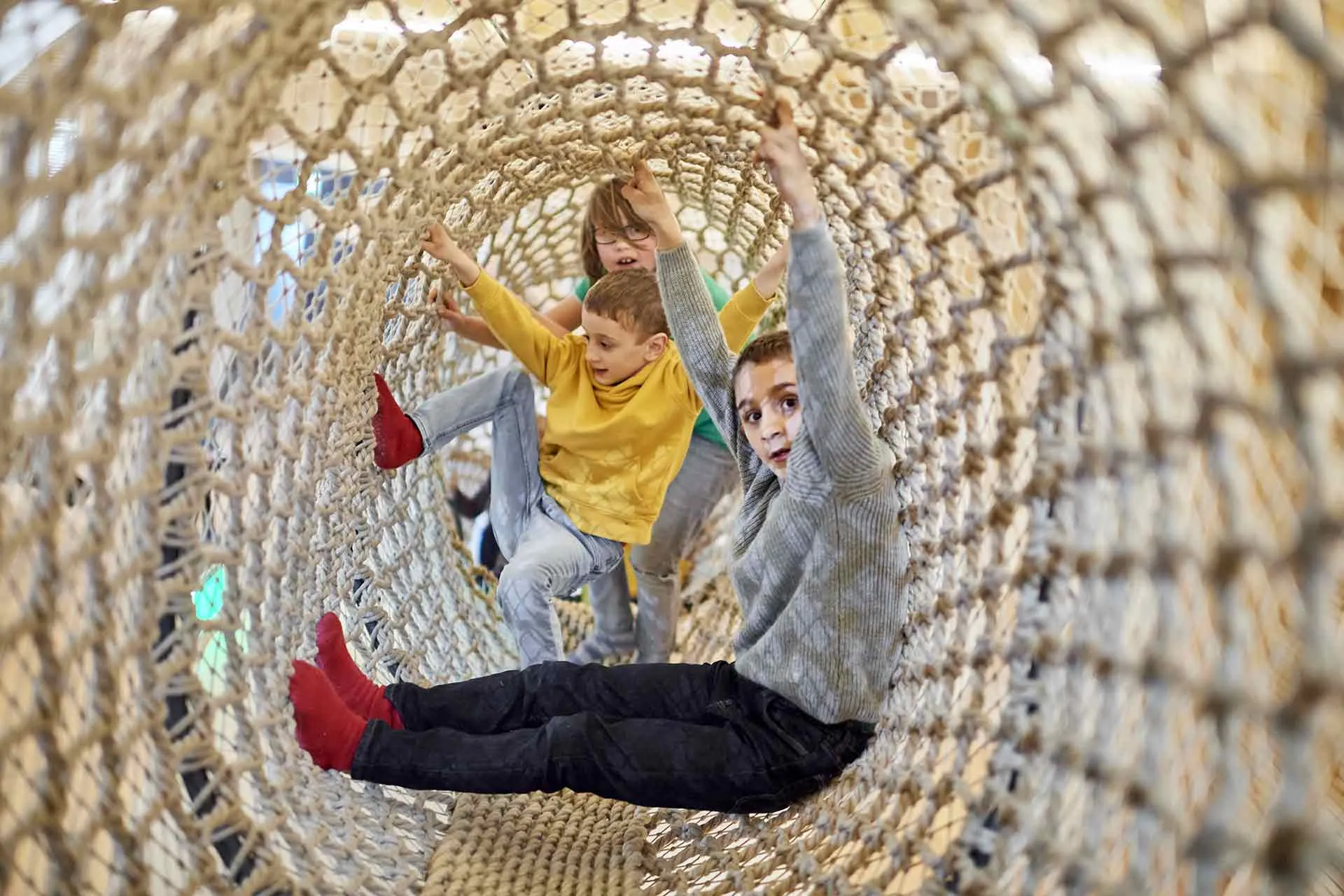 Drei Kinder turnen im ANOHA in der Kletterschlange.