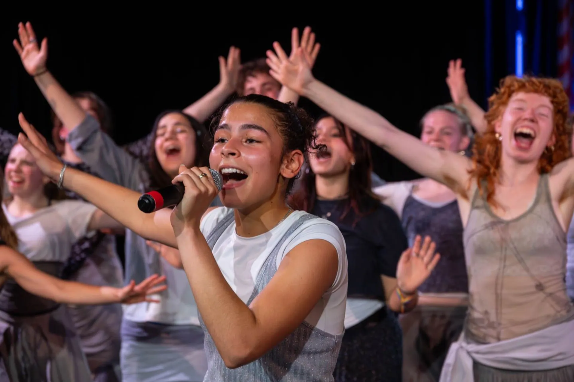 A group of people are singing with their hands in the air.