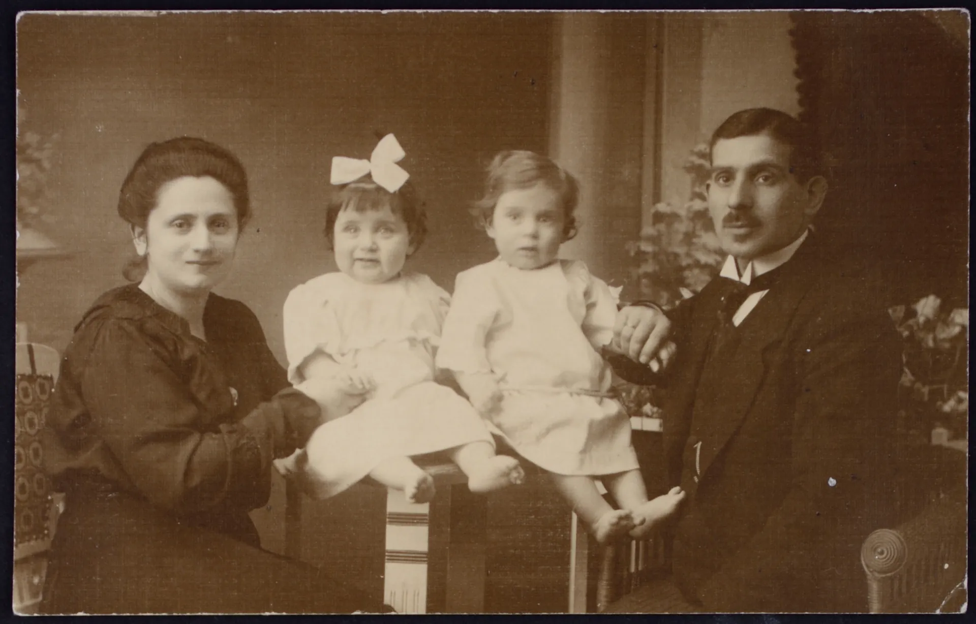 Ein altes schwarz-weiß Familienbild. Zu sehen links eine Frau (die Mutter). In der Mitte zwei kleine Kinder. Rechts ein Mann (der Vater)