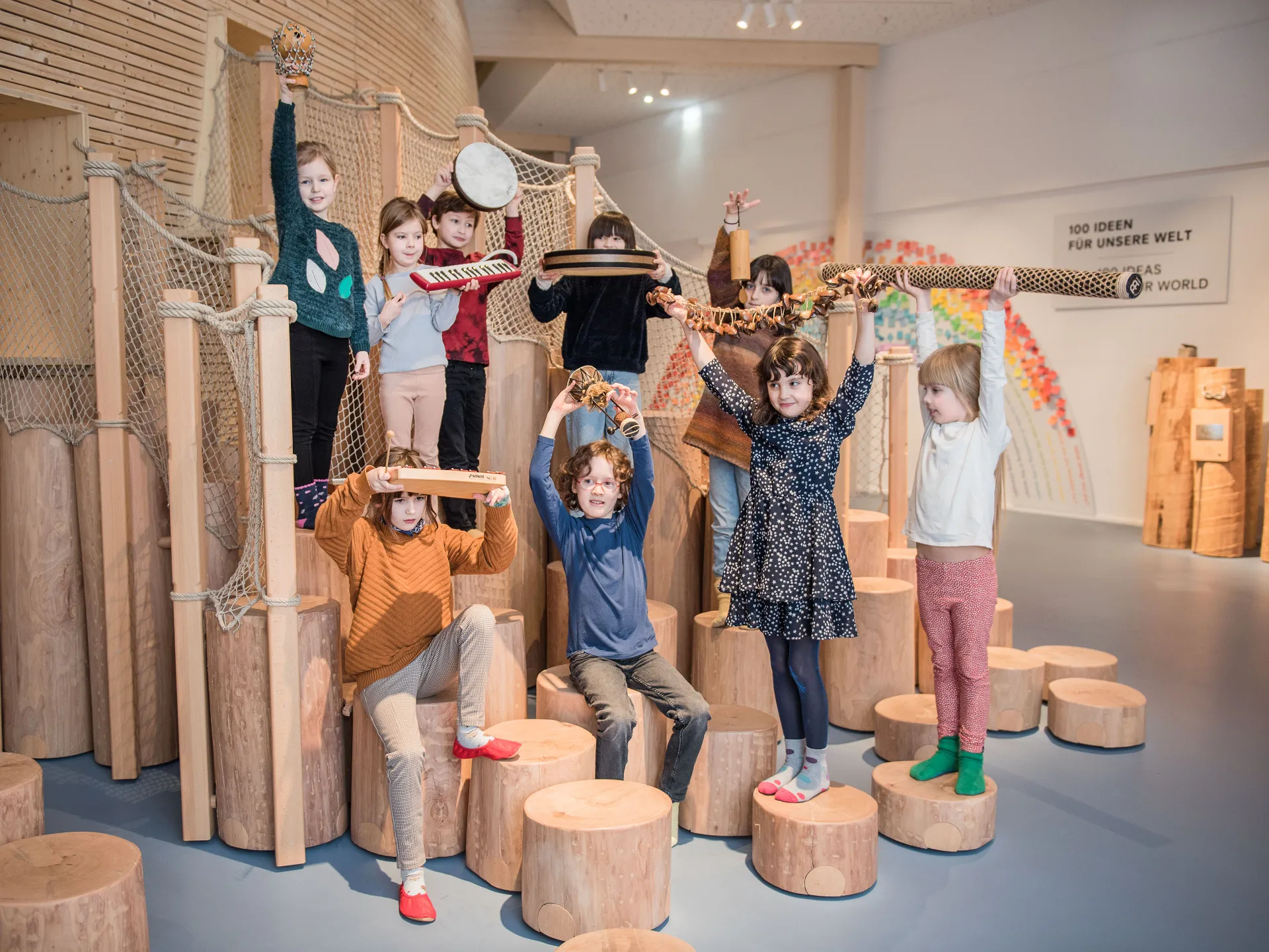 Neun Kinder stehen im Klanglabor im Kindermuseum ANOHA des Jüdischen Museums und halten Gegenstände in der Hand.