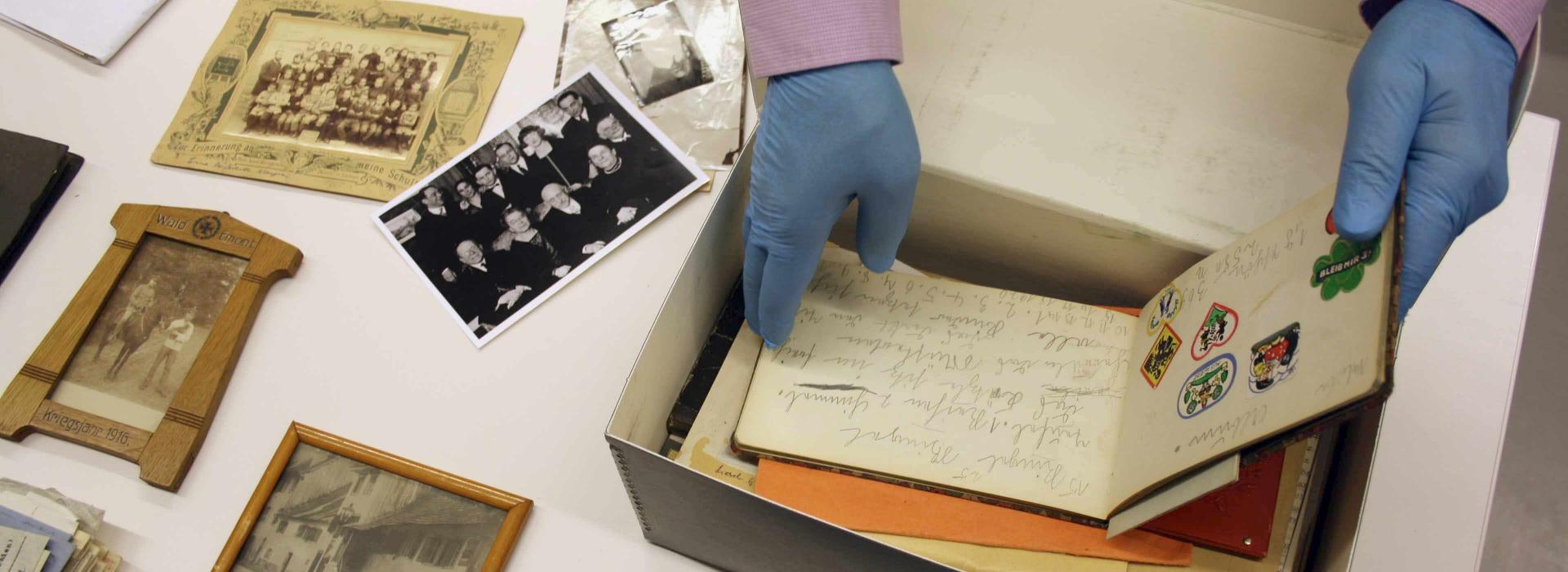 Hands reach into a box of letters, photos and documents.