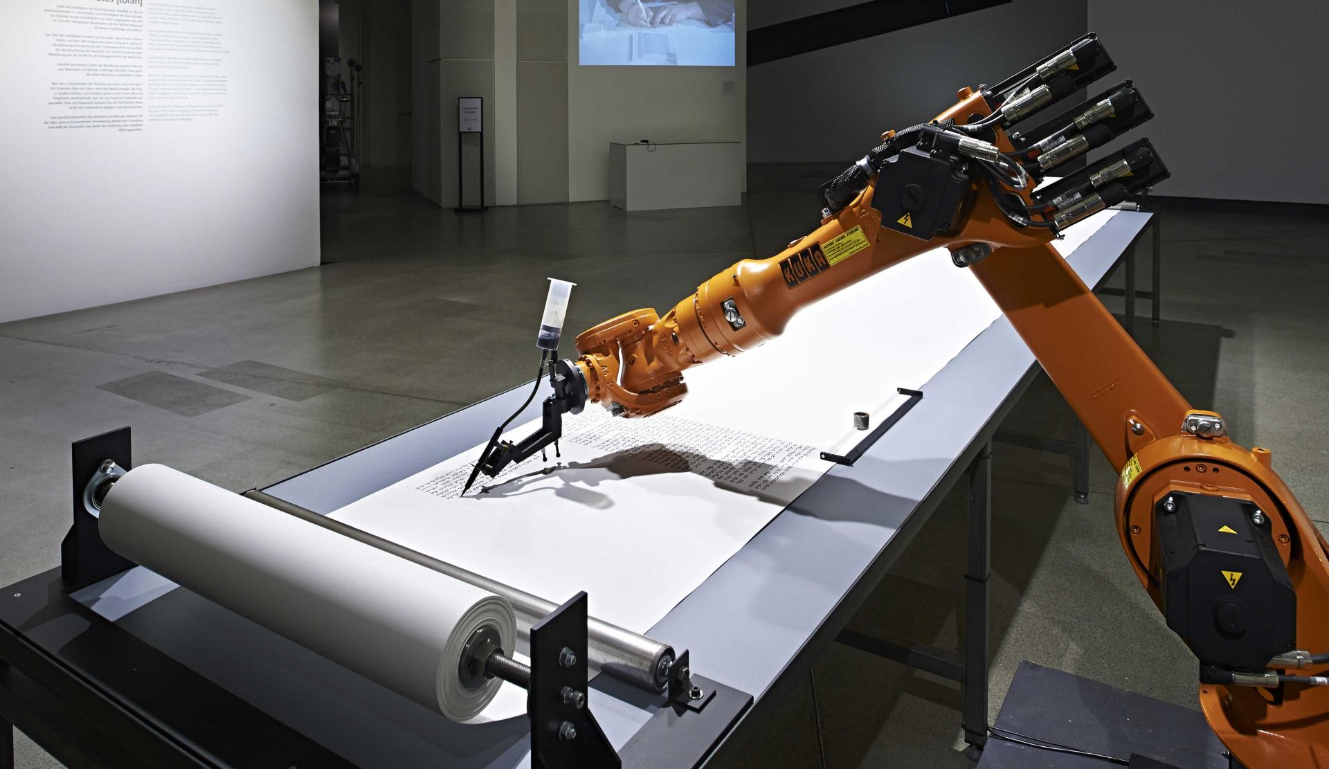 A robot arm with a fountain pen is writing on a Torah scroll