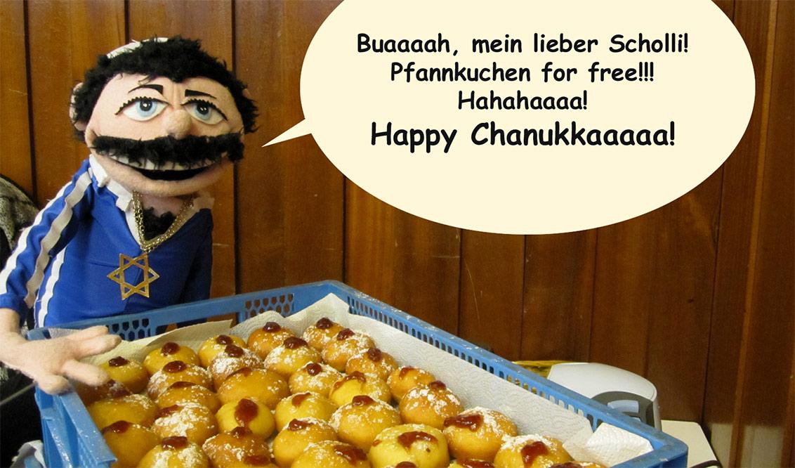 A puppet in a blue shirt with the star of David, in front of a crate of Berliner hotcakes with a speech bubble, “Oooh, my oh my! Hotcakes for free!!! Hahahaaaa! Happy Hanukkaaaah!”