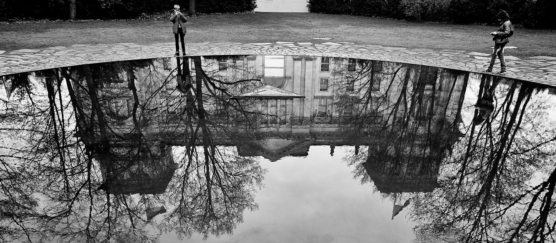 A building is reflected in the water, black and white photo.