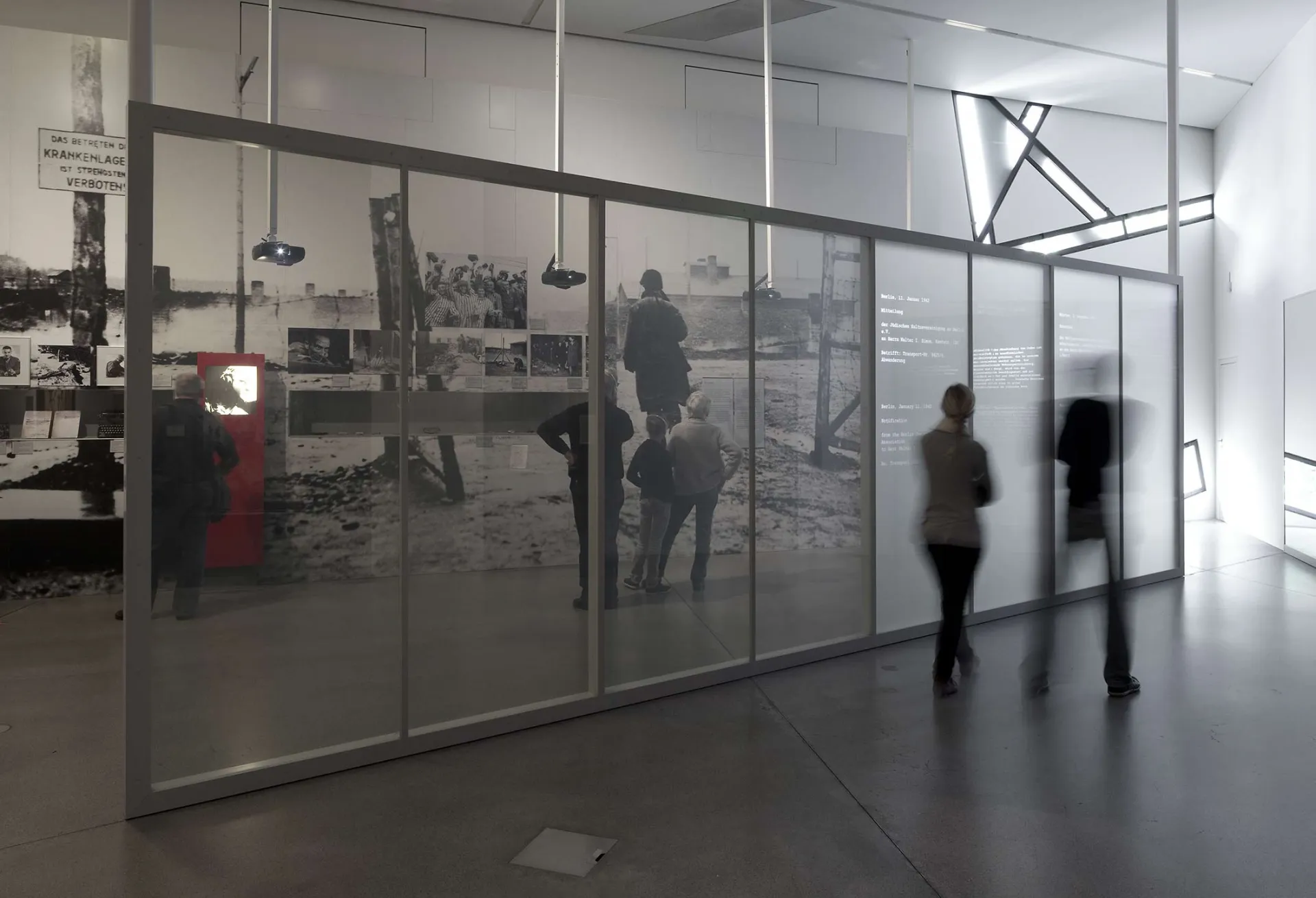 	Ausstellungsbesucher*innen vor einer Glaswand, auf die Dokumente projiziert werden
