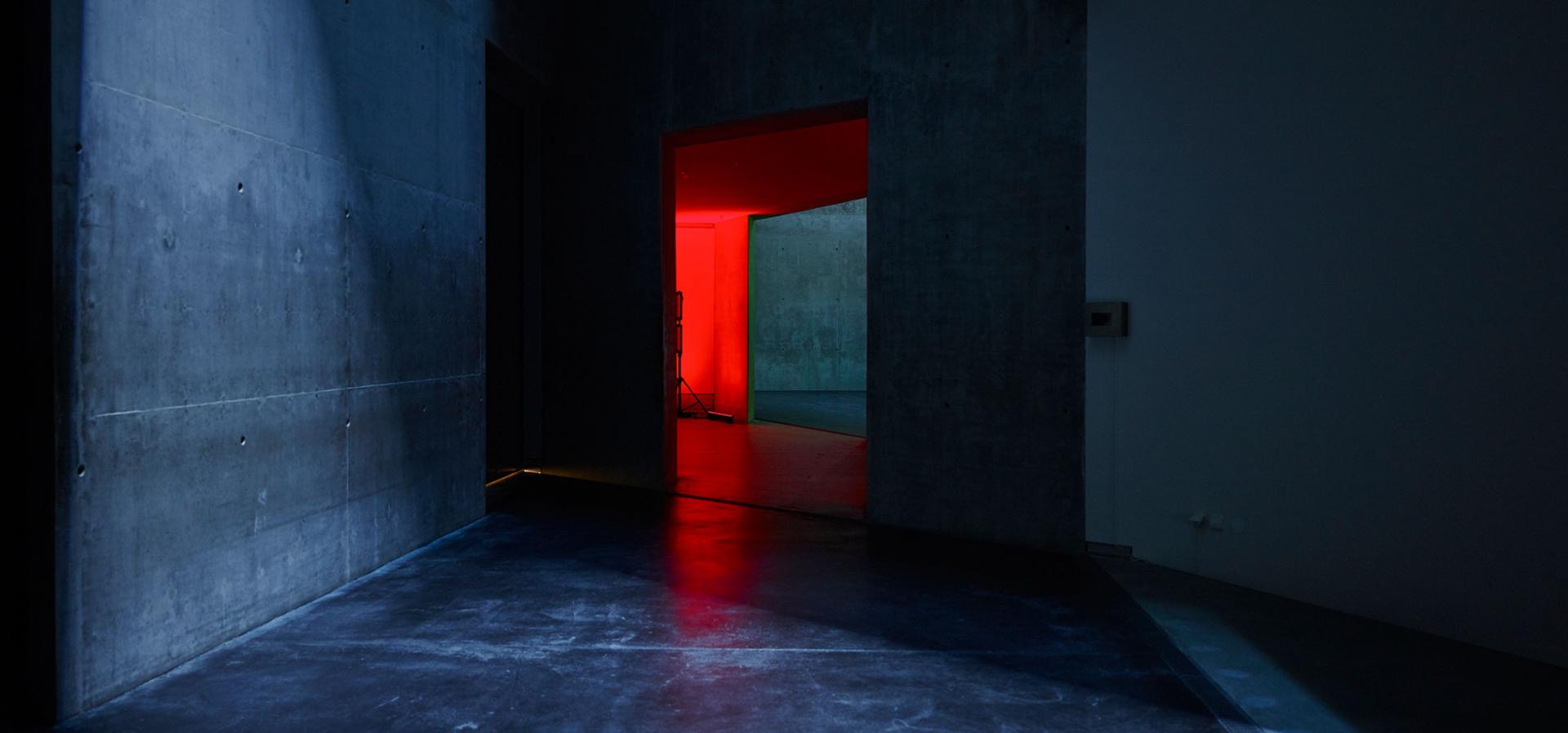 Ein dunkler Gang, durch eine Tür am ende dringt rotes Licht.