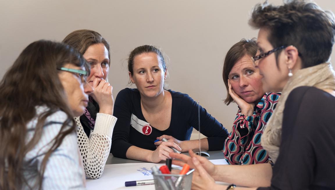 Five women in conversation around a table