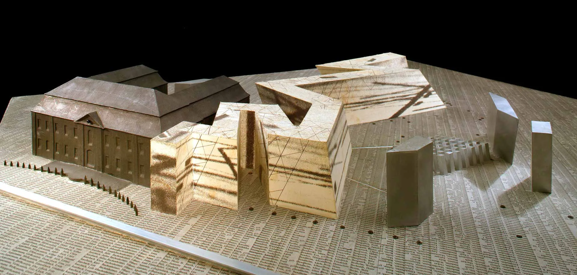 Architekturmodell des Jüdischen Museums Berlin aus Holzwerkstoff und Karton mit bedrucktem und grau gefärbten Papier beklebt, auf dem Untergrund stehen viele Namen.
