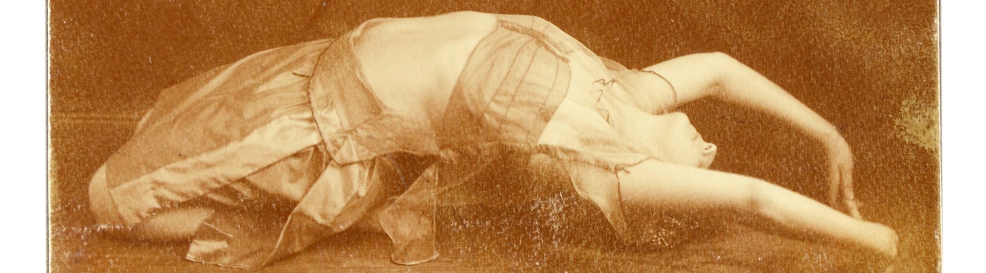 Old photographie showing a woman lying on the floor during a dance performance