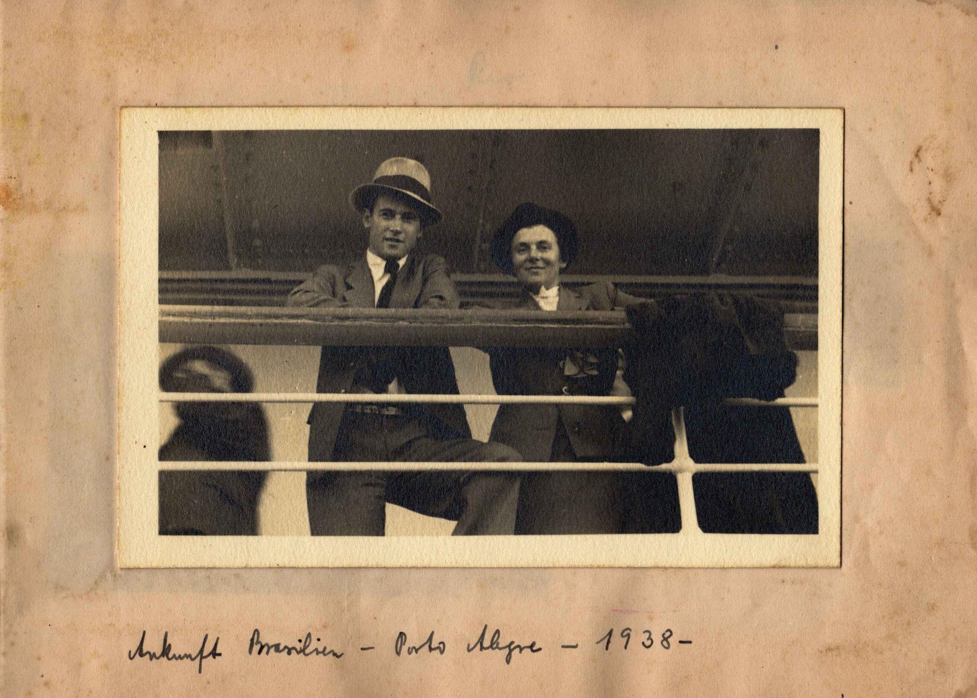 Schwarz-weiß Foto von einem Mann und einer Frau, die an einer Schiffsrehling lehnen, darunter handschriftlich: Ankunft Brasilien - Porto Alegre - 1938.