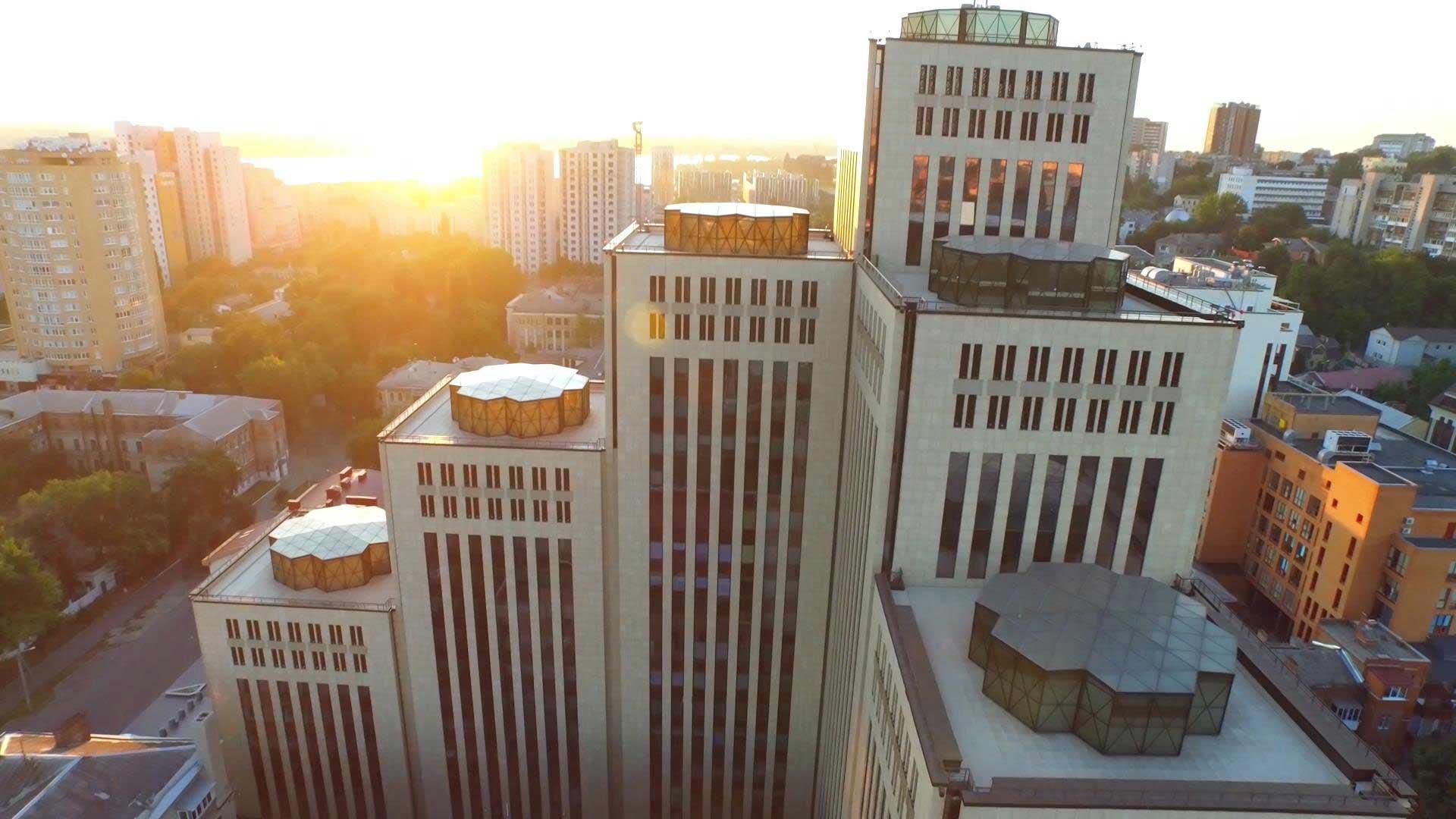 Vogelperspektive auf eine Stadt, im Vordergrund ein modernes Gebäude mit vielen hohen Türmen.