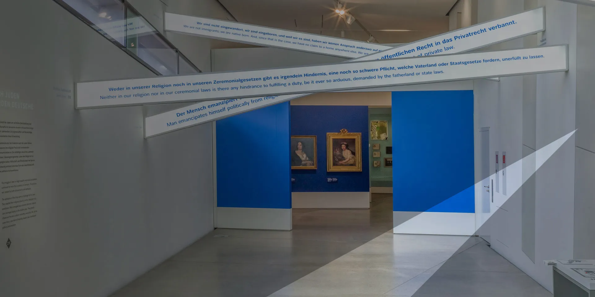 illuminated lettering with the French term égalité, illuminated signs with text, painting in the background. The image is with a gray veil that suggests the JMB logo.