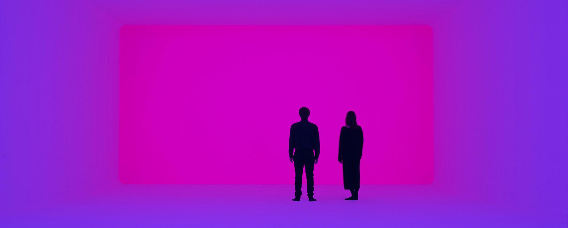 Zwei Menschen stehen in einem Raum aus blauem und violettem Licht