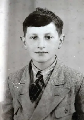 Black and white photo: Portrait of a dark-haired boy. He looks friendly into the camera.