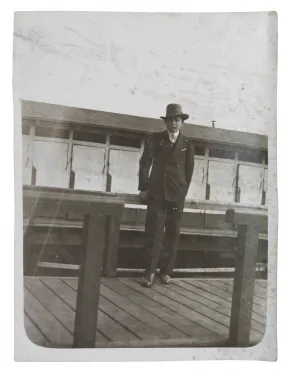 Black-and-white photo of a teenager standing on a wooden walkway 