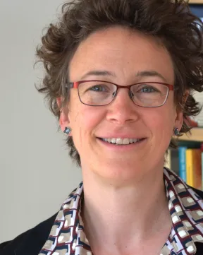 Eine Frau lacht in die Kamera. Sie tr&auml;gt eine Brille.