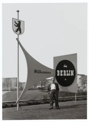 Fred Stein, hinter ihm Schilder mit der Aufschrift &raquo;Willkommen in Berlin&laquo;.