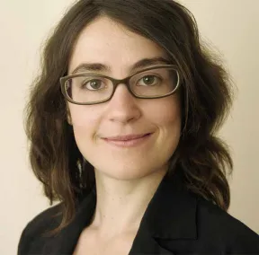 Portrait of a woman with glasses who smiles and looks directly into the camera