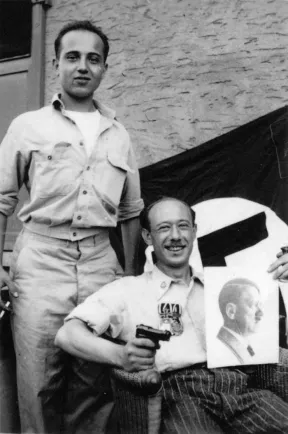 Schwarz-Wei&szlig;-Foto zweier M&auml;nner: Einer sitzt mit Pistole in der rechten und Hitler-Foto in der linken Hand, einer steht schr&auml;g hinter ihm, daneben schaut eine Hakenkreuz-Flagge heraus.