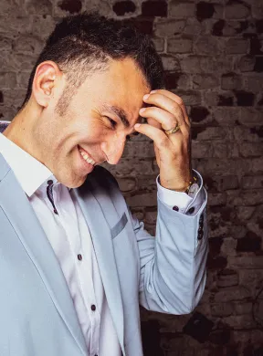 A man grabs his head and grins.