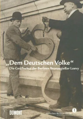 Historisches Foto, das zeigt, wie zwei M&auml;nner eine Inschrift am Berliner Reichstag anbringen.