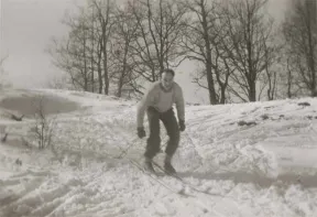 In the black-and-white photo, Walter is skiing up a small slope.