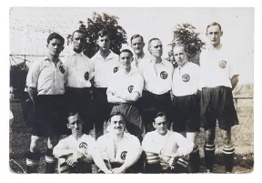 Schwarz-Wei&szlig;-Foto einer Fu&szlig;ballmannschaft mit wei&szlig;en Trikots und dunklen Hosen.