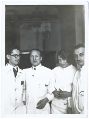 Schwarz-Wei&szlig;-Foto: Erich Simenauer steht als zweiter von links in einer Gruppe von vier Personen, rechts neben ihm steht eine Frau, die kess in die Kamera schaut, alle tragen wei&szlig;e Kittel. Keiner der anderen Abgebildeten ist namentlich bekannt.