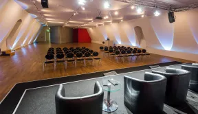 Blick in den Grossen Saal mit Stuhlreihen und B&uuml;hne