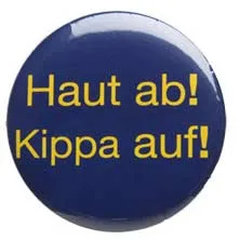 Ansteckbutton mit der Aufschrift &raquo;Haut ab! Kippa auf!&laquo;, gelbe Schrift auf blauem Hintergrund