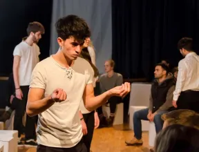 Young people stand in the room and rehearse for a performance