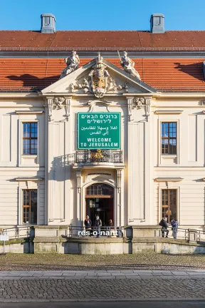 The colour photo shows the fa&ccedil;ade of the Jewish Museum Berlin with a traffic sign with the inscription "Welcome to Jerusalem" in English, Arabic and Hebrew.