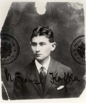 Schwarz-wei&szlig;es Passbild eines jungen Mannes mit gegeeltem Mittelscheitel, auf dem Foto sind Stempel und die Unterschrift: Dr. Franz Kafka.