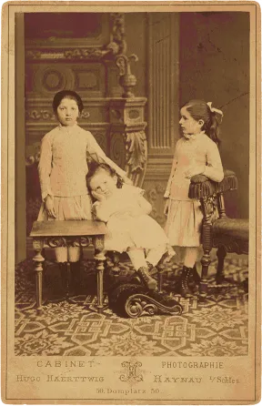 Historische Schwarz-Wei&szlig;-Fotografie von drei Kindern in wei&szlig;en Kleidern.