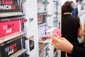 Eine Hand &ouml;ffnet ein Fach des Kunstautomaten
