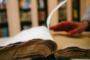 Hand bl&auml;ttert aufgeschlagenes dickes, altes Buch um