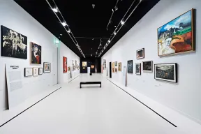 Blick in einen wei&szlig; gehaltenen Ausstellungsraum mit Bildern an den W&auml;nden