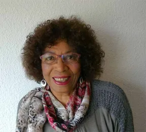 Portr&auml;t einer Frau mit Brille, die l&auml;chelt und direkt in die Kamera schaut