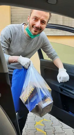 Blick vom Beifahrersitz auf einen Mann mit T&uuml;te und Handschuhen, der an der Fahrert&uuml;r ins Auto steigt