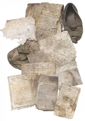 Verschiedene zerknitterte Schriftst&uuml;cke mit hebr&auml;ischen Buchstaben, ein Schuh und eine Tasche.