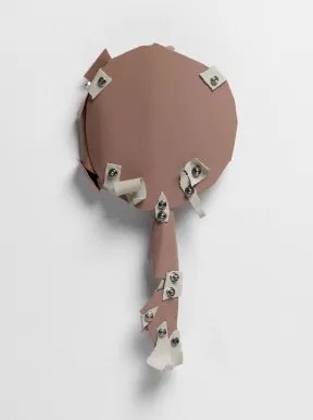 Hellbraunes, handspiegelf&ouml;rmiges, hellbraunes Objekt, auf dem mit Nieten beigefarbene kleinere Fl&auml;chen angebracht sind.