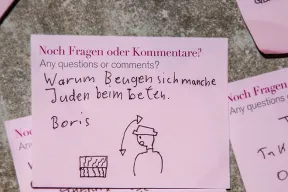 Ein pinker Post-it-Zettel beschriftet mit &bdquo;Warum Beugen sich manche Juden beim beten?&ldquo;
