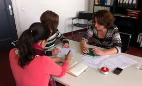 Drei Redakteurinnen sitzen um einen Tisch und diskutieren.