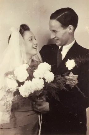 Schwarz-wei&szlig;-Fotografie eines Paares mit Blumenstrau&szlig; und Schleier, an seinem Jacket ein &bdquo;Judenstern&ldquo;