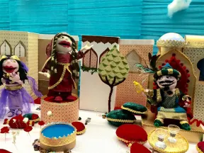 A rag doll sits on a throne and looks at a female rag doll standing on a pedestal
