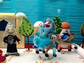 Two puppets in front of a blue screen, one is sittung on an Horse