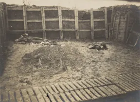 Black and white photograph of a trench with a dead soldier.